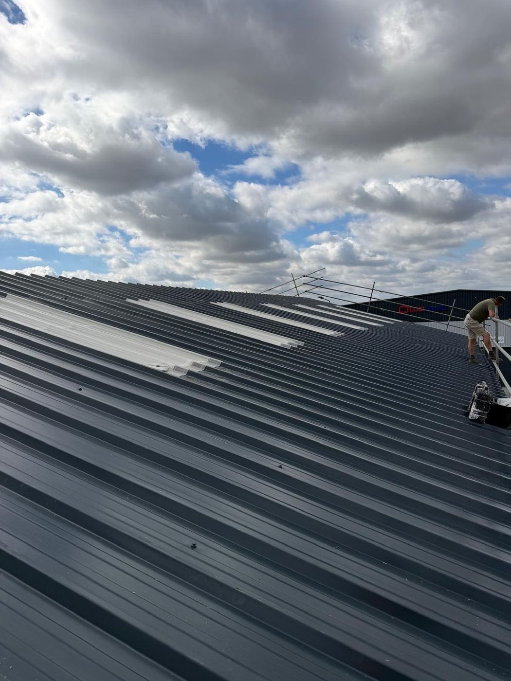 Industrial roof with new grey profiled sheets and rooflight strips being installed by UDM