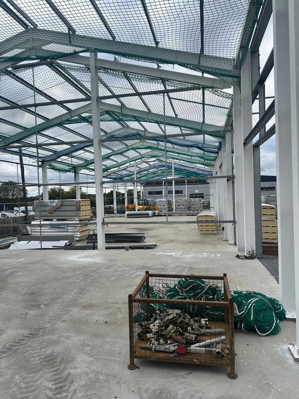 Steel rafters and cladding materials staged inside the Tekla-designed frame